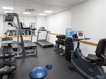 a gym with cardio equipment and weights on the floor